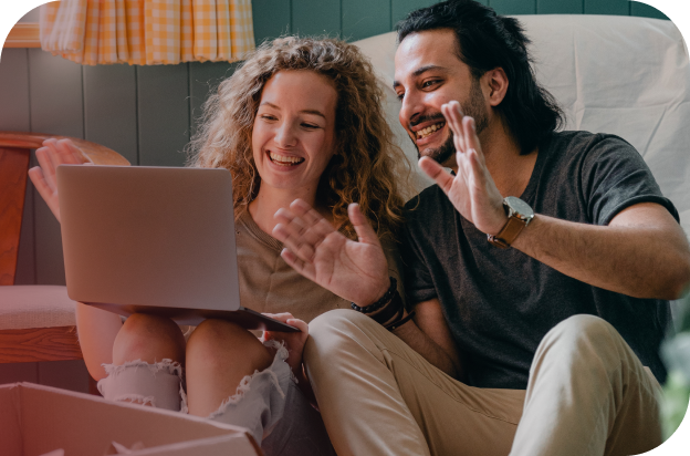 Casal sentado no chão sorrindo ao olhar para um notebook